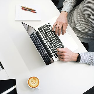 デスクでノートパソコンに文字を打ち込む手元の様子