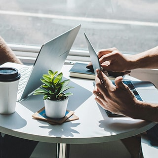 小さなテーブルに向かい合い、ノートパソコンを開いて打ち合わせをする2人の様子