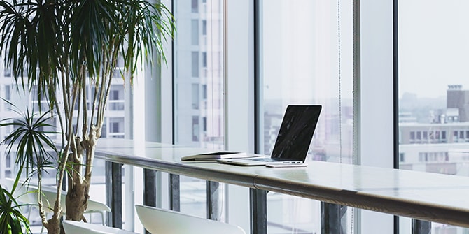明るい光が差し込むオフィスのデスクとノートパソコン